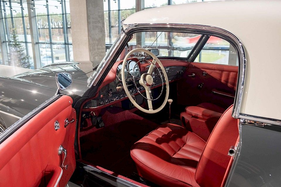 Eleganckie wnętrze klasycznego Mercedesa-Benz z czerwonymi skórzanymi siedzeniami, kremową kierownicą i polerowanymi chromowanymi detalami, odzwierciedlające ponadczasowy design.